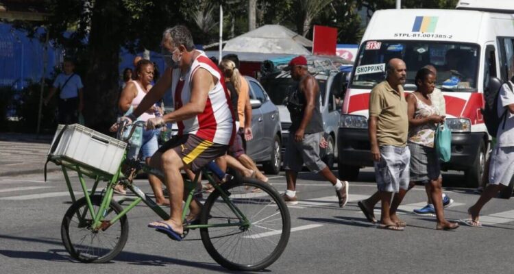 Calor em Bangu | homem de bicicleta vestido com a camisa do bangu atravessa rua sob forte sol e calor