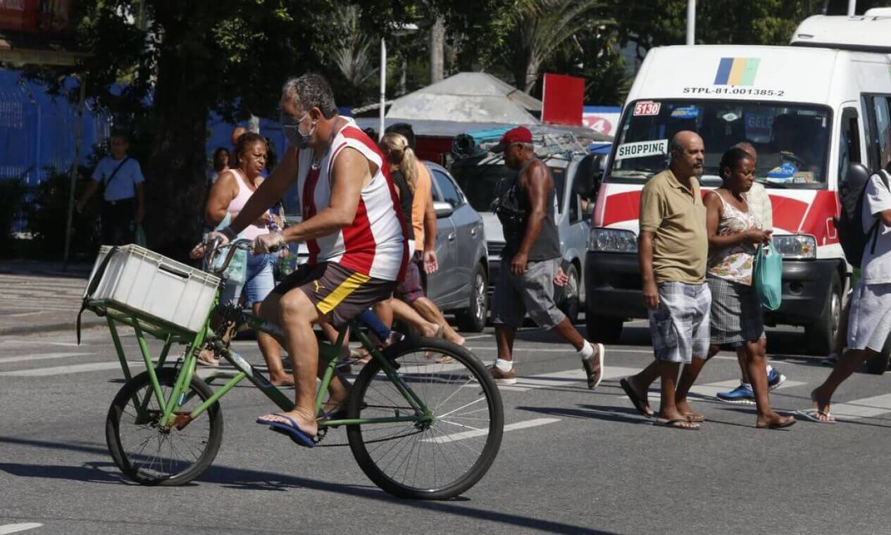 Calor em Bangu | homem de bicicleta vestido com a camisa do bangu atravessa rua sob forte sol e calor